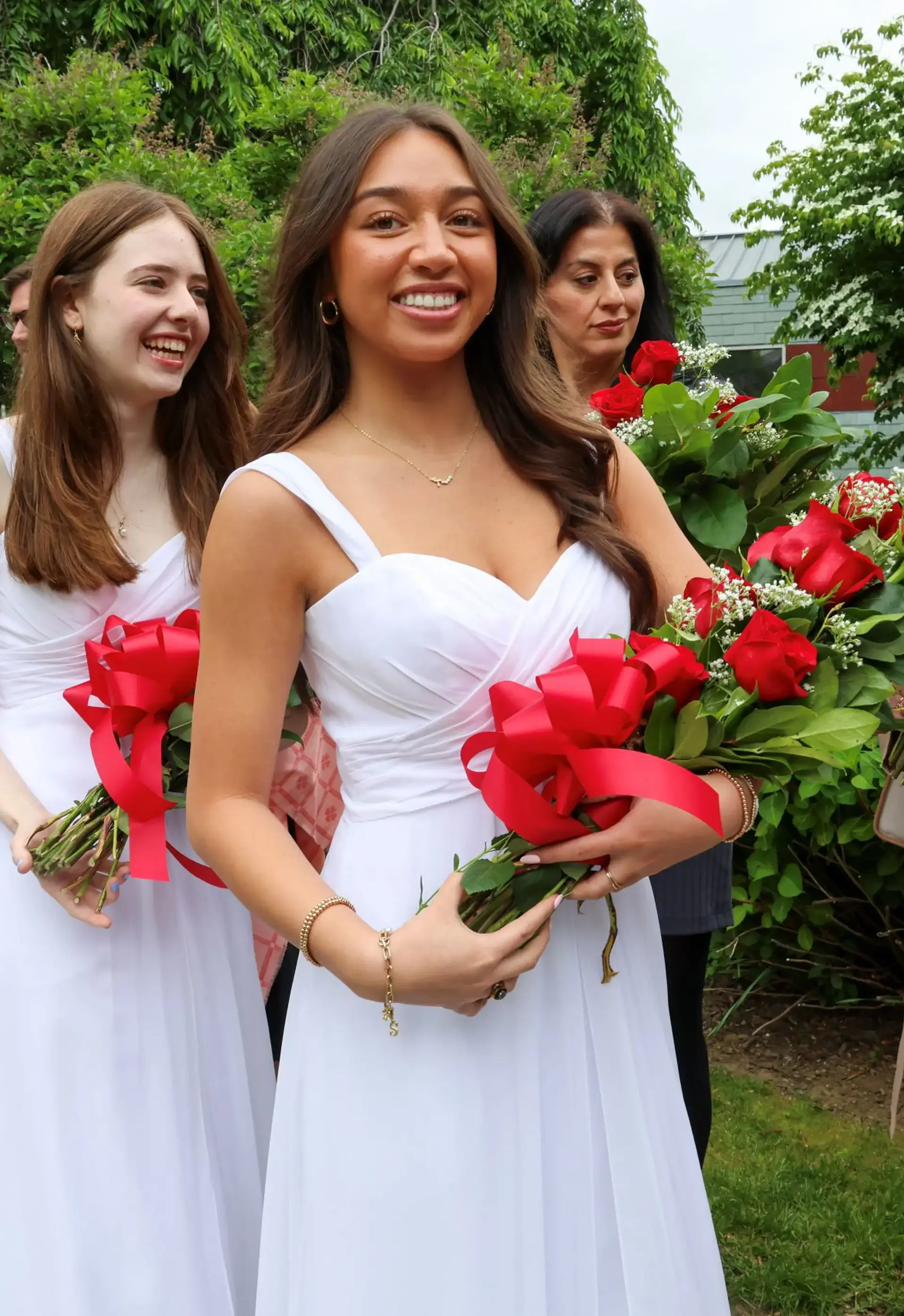 Holy Child students on graduation day in white dresses with red roses.